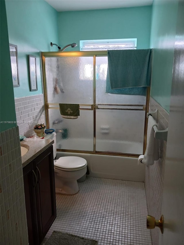 full bathroom with tile walls, toilet, enclosed tub / shower combo, tile flooring, and vanity