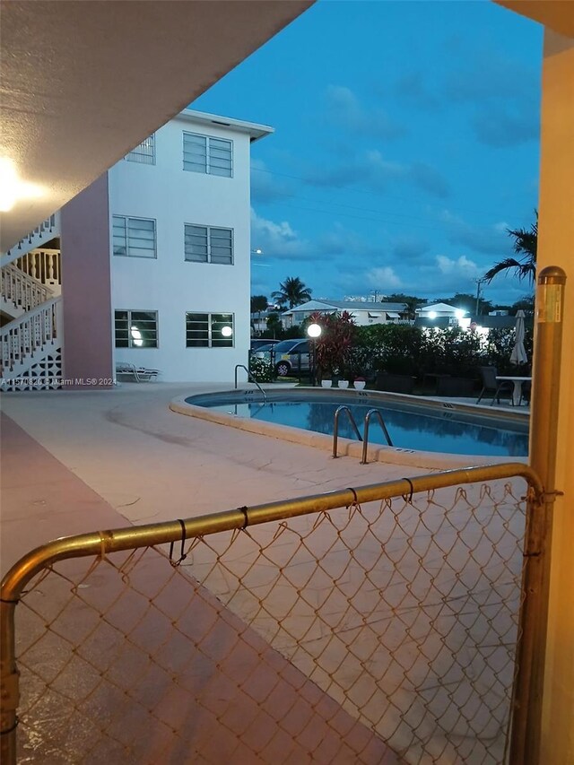 pool at dusk with a patio area