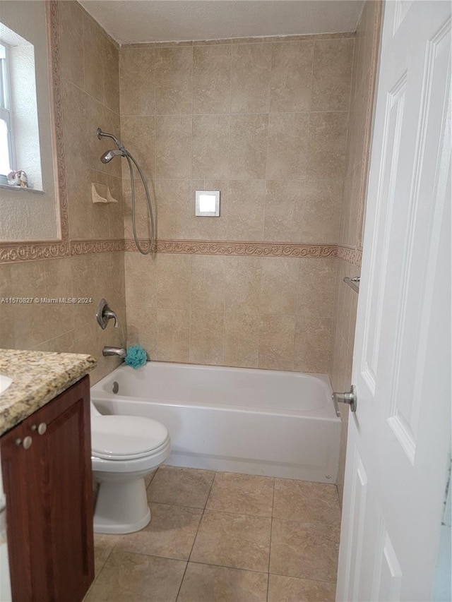 full bathroom featuring tile patterned flooring, toilet, tiled shower / bath combo, and vanity