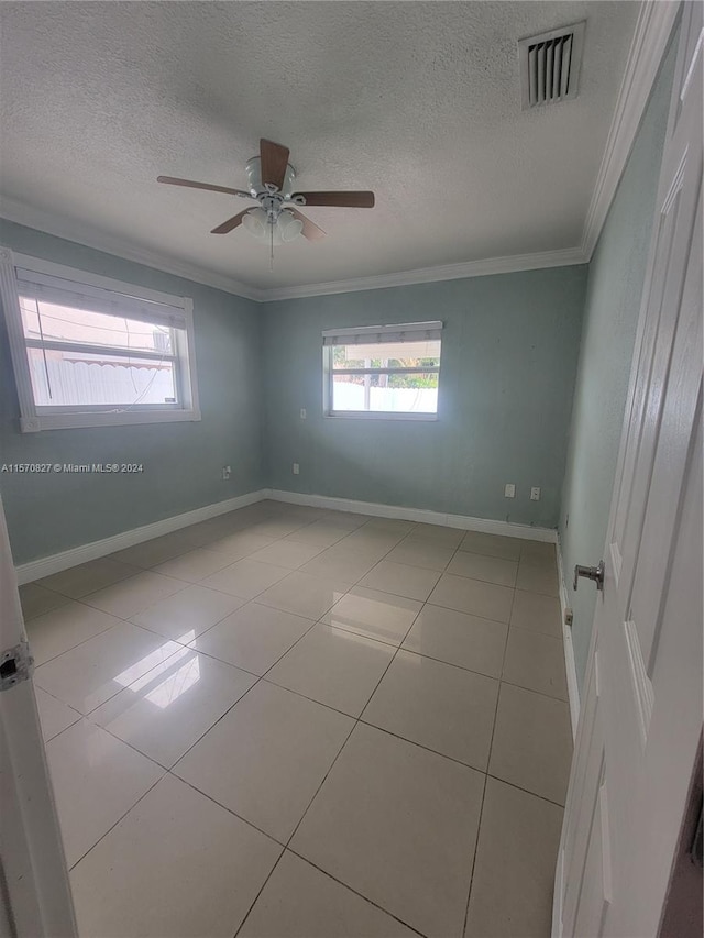 tiled empty room with ornamental molding, a textured ceiling, and ceiling fan