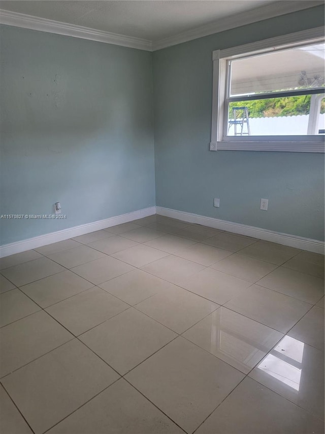 spare room featuring tile patterned flooring and ornamental molding