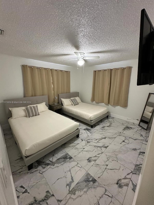 tiled bedroom featuring ceiling fan and a textured ceiling