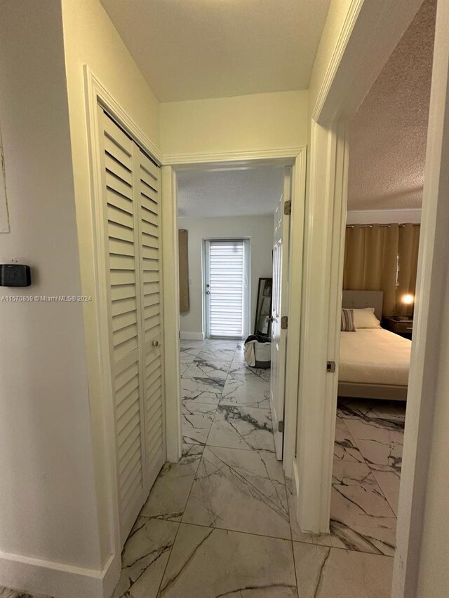 corridor featuring a textured ceiling and light tile flooring