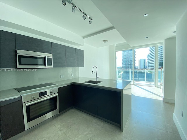 kitchen featuring light tile floors, sink, stainless steel appliances, kitchen peninsula, and track lighting