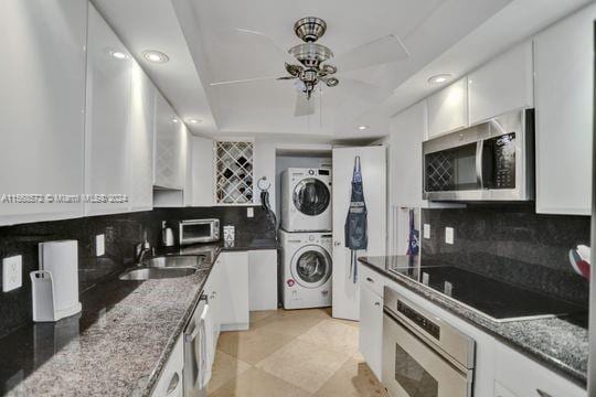 1121 Crandon Blvd Unit F906, Key Biscayne, FL 33149 - kitchen featuring white cabinetry, stacked washer and dryer, appliances with stainless steel finishes, and a sink