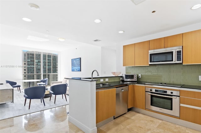 kitchen featuring appliances with stainless steel finishes, light tile floors, sink, backsplash, and kitchen peninsula