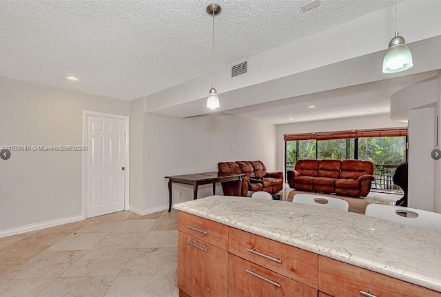 kitchen with a textured ceiling, light stone countertops, light tile floors, and decorative light fixtures