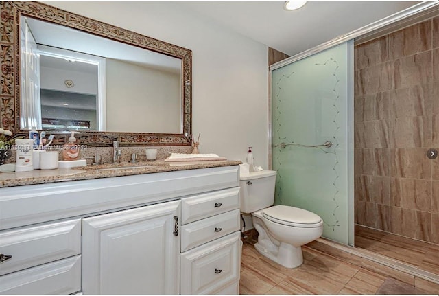 bathroom with a shower with door, tile floors, toilet, and vanity with extensive cabinet space