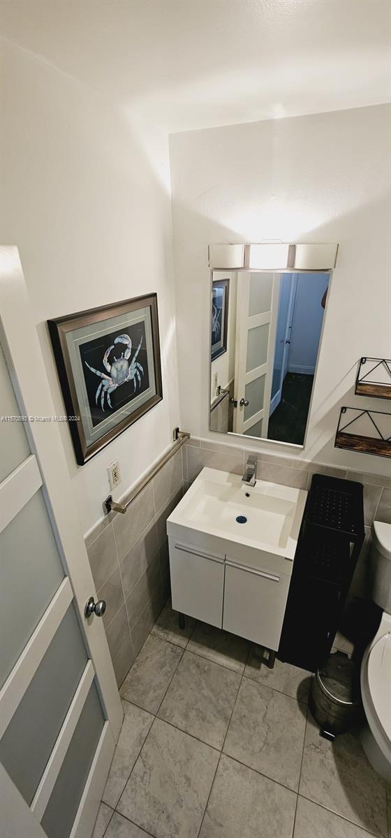 bathroom featuring tile flooring, vanity, and toilet