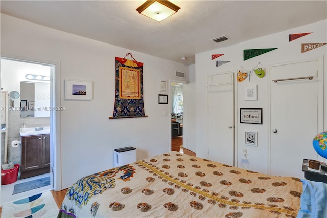 bedroom featuring a closet, light hardwood / wood-style floors, ensuite bath, and sink