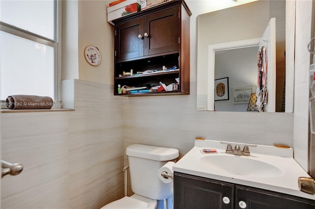 bathroom with tile walls, vanity, and toilet