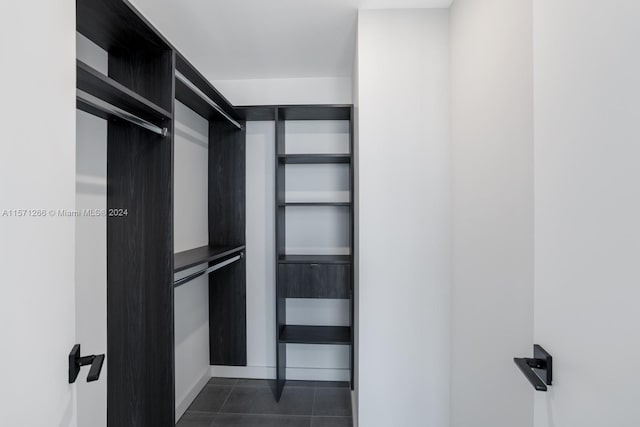 walk in closet featuring dark tile floors