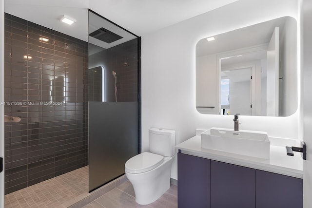 bathroom featuring vanity, tile floors, toilet, and a tile shower