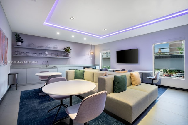 tiled living room featuring a raised ceiling and sink