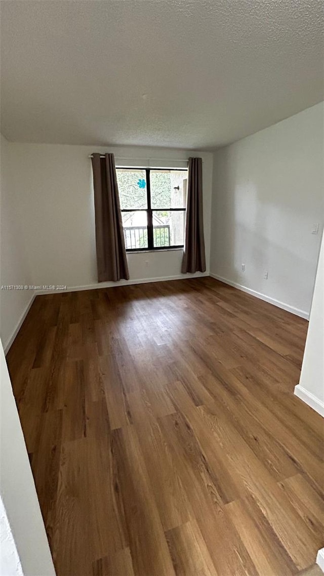 unfurnished room with dark hardwood / wood-style flooring and a textured ceiling