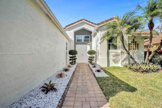 view of exterior entry with a yard