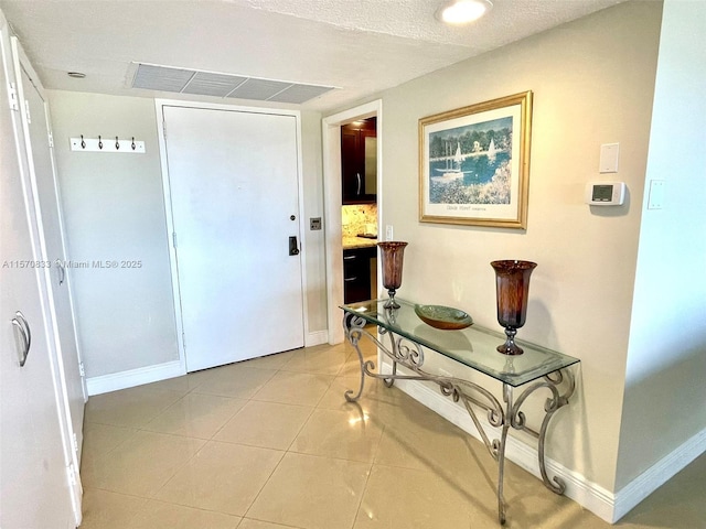 hallway featuring a textured ceiling and light tile patterned flooring