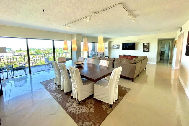 dining space with a textured ceiling, rail lighting, and light tile patterned flooring