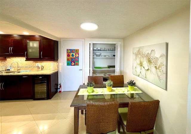 kitchen featuring a textured ceiling, light tile patterned floors, tasteful backsplash, wine cooler, and sink