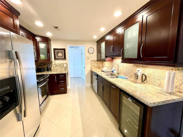 kitchen with light stone counters, stainless steel appliances, wine cooler, backsplash, and sink