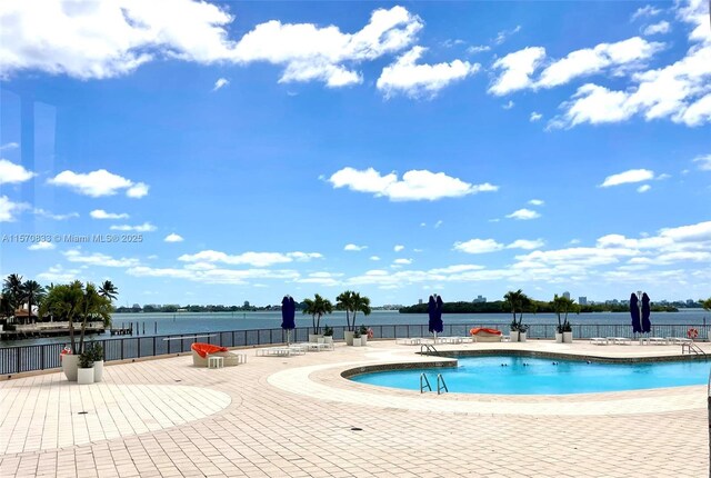 view of swimming pool featuring a patio and a water view