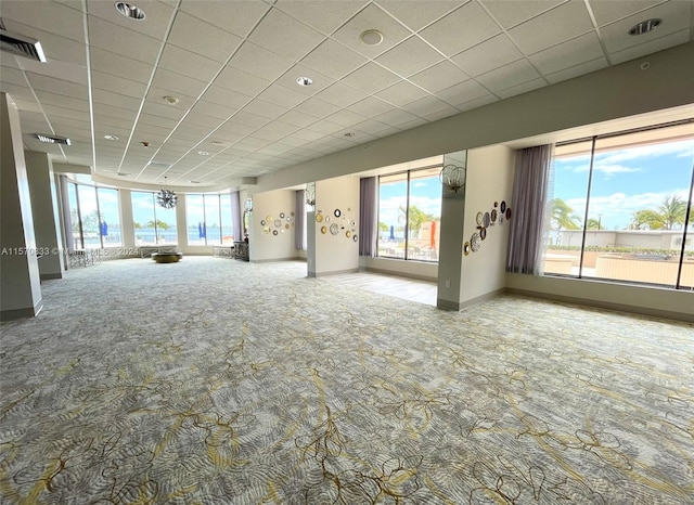 carpeted spare room featuring a healthy amount of sunlight and a paneled ceiling