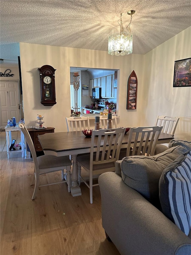 dining room featuring a textured ceiling, a notable chandelier, and hardwood / wood-style flooring