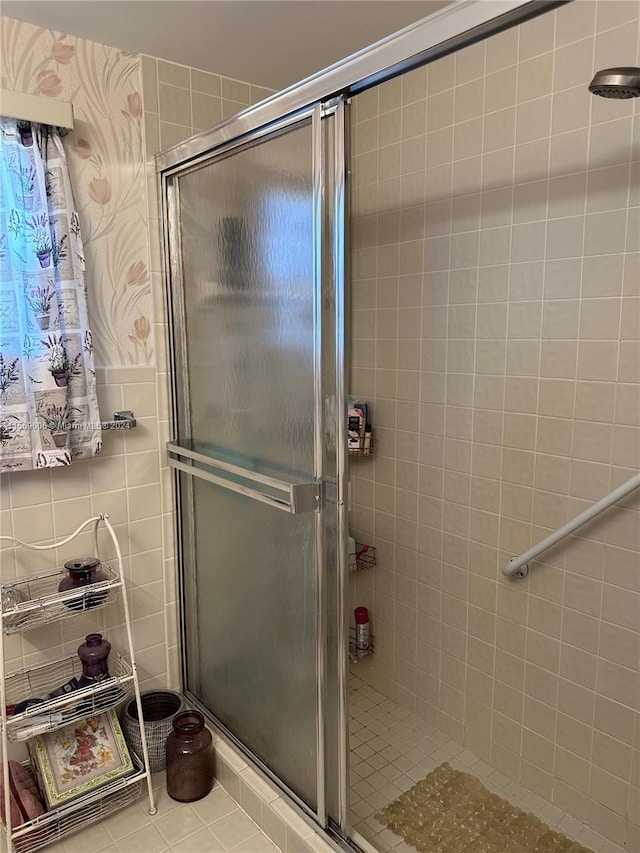 bathroom with a shower with shower door and tile floors