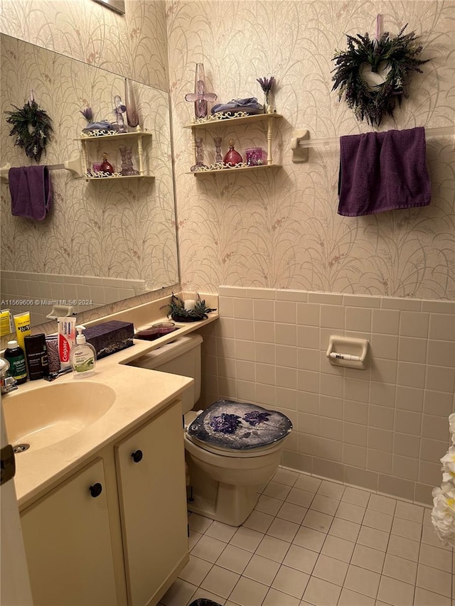 bathroom featuring tile floors, vanity, toilet, and tile walls