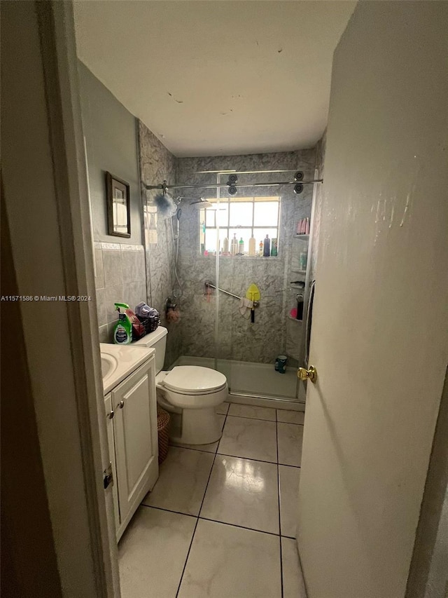 bathroom with vanity, tile patterned floors, toilet, and a tile shower