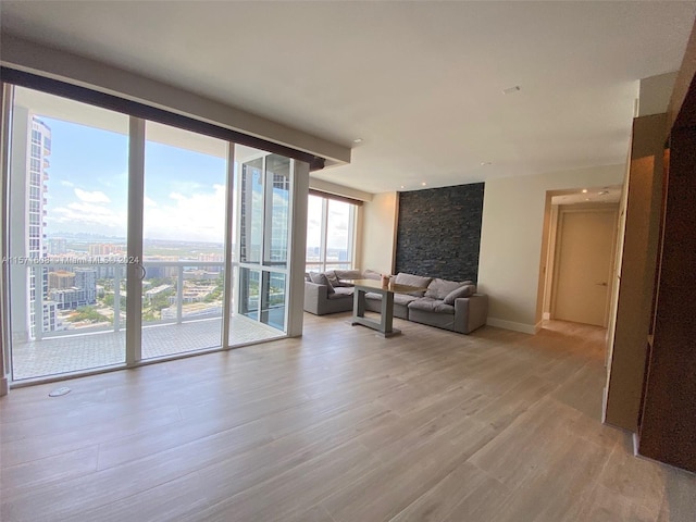 unfurnished living room featuring floor to ceiling windows and light wood-type flooring