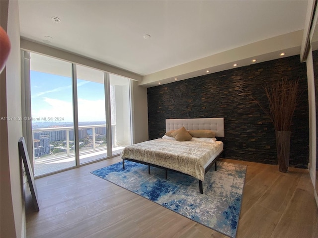 bedroom with floor to ceiling windows, hardwood / wood-style flooring, and access to exterior