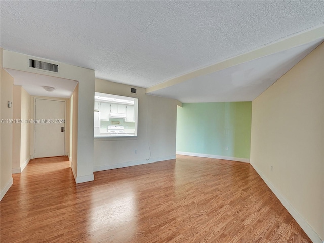 spare room featuring light hardwood / wood-style flooring and a textured ceiling