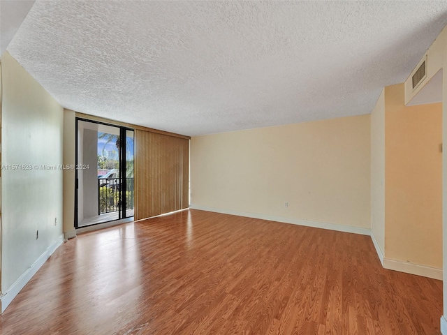 spare room featuring light hardwood / wood-style floors, a wall of windows, and a textured ceiling