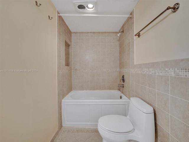 bathroom with tile walls, tile floors, toilet, and tiled shower / bath