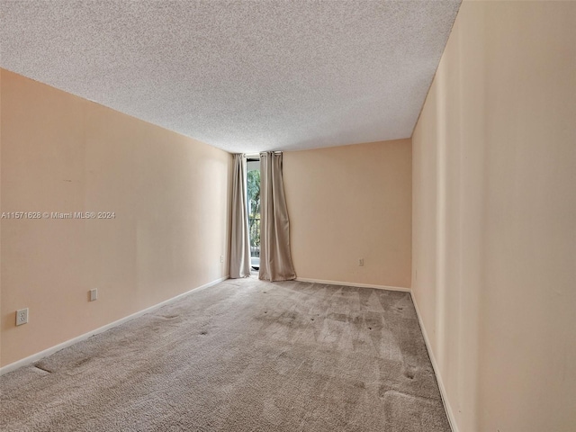 empty room with light colored carpet and a textured ceiling