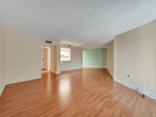 spare room featuring light hardwood / wood-style flooring and a textured ceiling