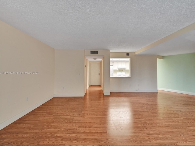 spare room with a textured ceiling and light wood-type flooring