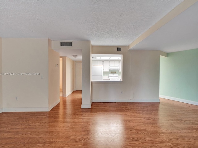 spare room with light hardwood / wood-style floors and a textured ceiling