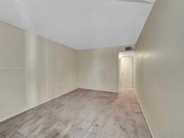 unfurnished room featuring light colored carpet and a textured ceiling