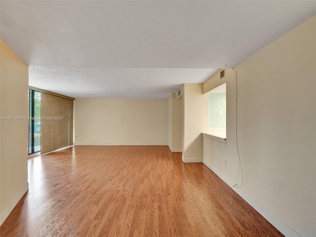 spare room with light hardwood / wood-style floors and a textured ceiling