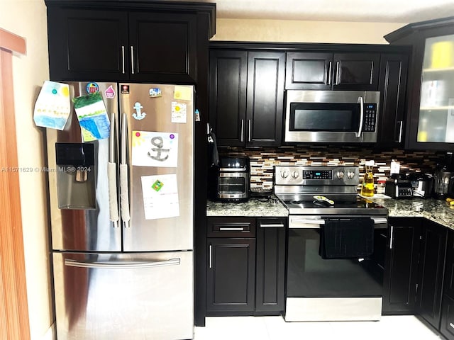 kitchen with decorative backsplash, stainless steel appliances, light stone counters, and light tile patterned floors