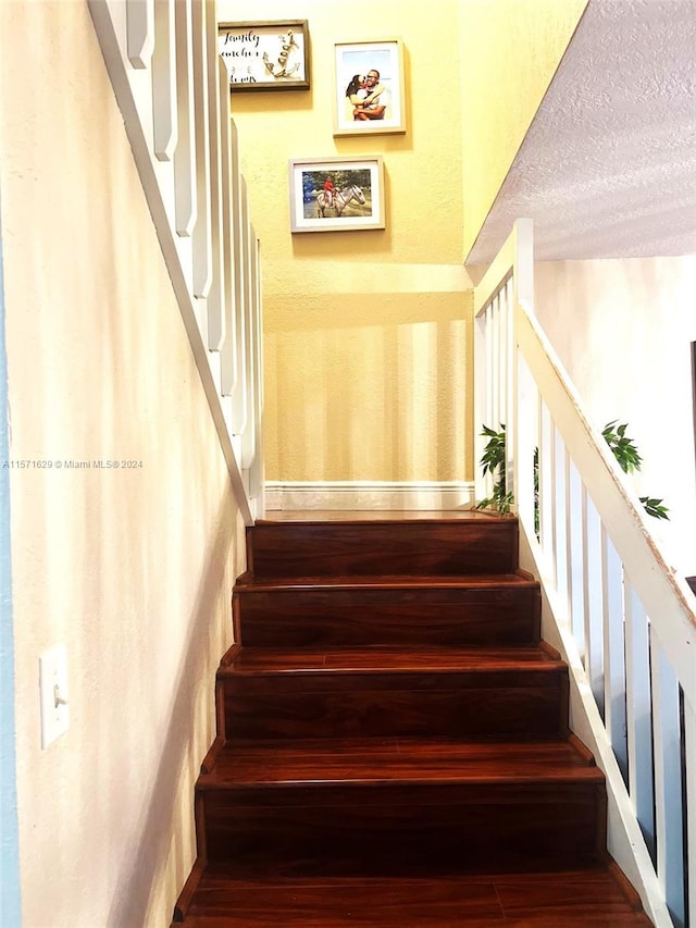 staircase featuring a textured ceiling