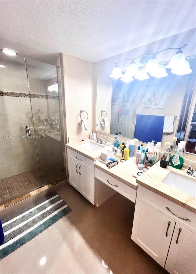 bathroom with a shower with shower door, vanity, and a textured ceiling