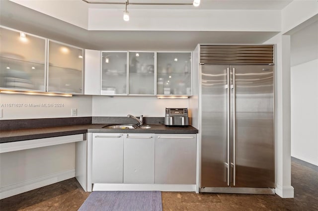 kitchen with rail lighting, stainless steel built in fridge, white cabinets, and sink