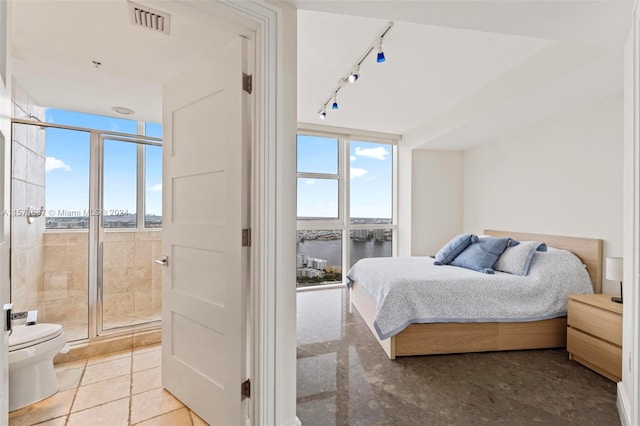 tiled bedroom featuring a water view, expansive windows, multiple windows, and track lighting