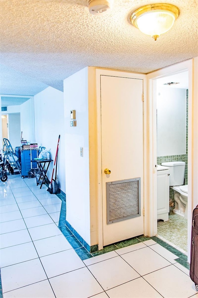 corridor featuring a textured ceiling and tile floors