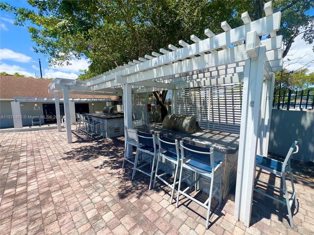 view of patio with a grill, area for grilling, an outdoor bar, and a pergola