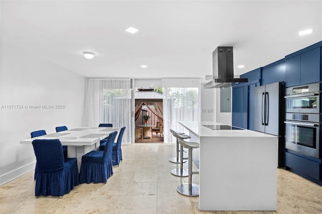 kitchen with island exhaust hood, appliances with stainless steel finishes, a kitchen breakfast bar, a wall of windows, and a center island