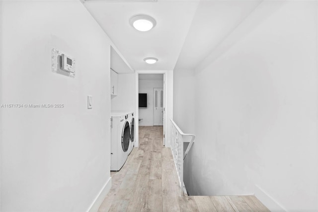 laundry area featuring washer and clothes dryer, cabinets, and light hardwood / wood-style flooring